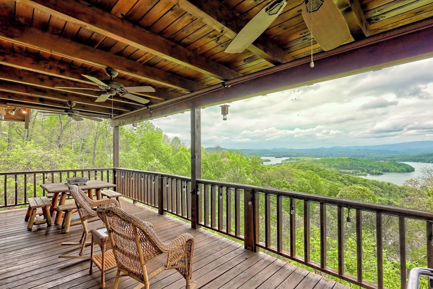 Eine Holzterrasse mit Gartenmöbeln und einem schönen Blick auf See und Wald.