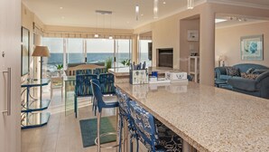 A modern kitchen with a large island, bar stools, and a view of the ocean.