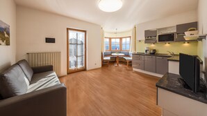 Eine moderne Küche mit eingebauten Geräten, ein Essbereich mit rundem Tisch und ein Wohnbereich mit einer Couch.