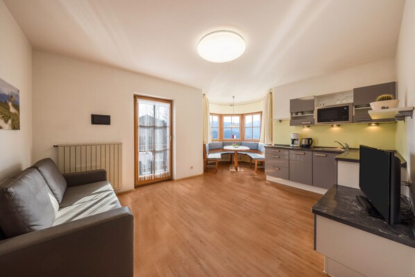 A modern kitchen with built-in appliances, a dining area with a round table, and a living space with a sofa.
