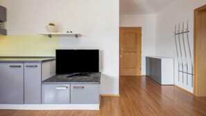 Eine moderne Küche mit grauen Schränken, einer schwarzen Arbeitsplatte und einer Holztür im Hintergrund.
