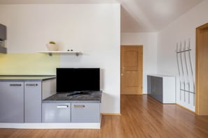 Eine moderne Küche mit grauen Schränken, einer schwarzen Arbeitsplatte und einer Holztür im Hintergrund.