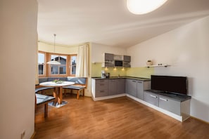 A compact kitchen with a dining area, built-in appliances, and a flat-screen TV.