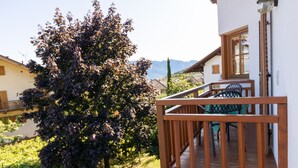 Eine Holzterrasse mit Geländer, einem Tisch und Stühlen, und ein Baum im Hintergrund.