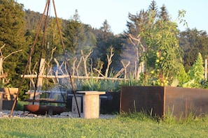 A rustic outdoor setting with a metal grill, a wooden table, and a planter box. - Hochhäderich Double Room - Nahturhof - Vacations.Naturally.Experience. (Krumbach)