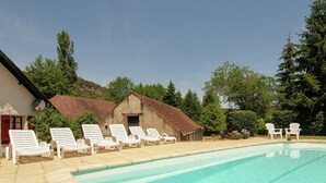 A swimming pool with white lounge chairs, a rustic building, and lush greenery. - Cottage in Vézac near Forest and Lake (Vezac)