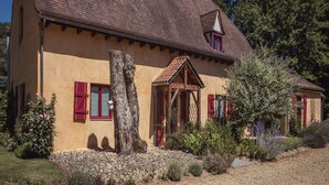 A traditional house with a sloped roof, a wooden porch, and a stone wall. - Cottage in Vézac near Forest and Lake (Vezac)