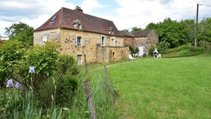A stone house with a red-tiled roof, a small garden, and a grassy lawn. - Holiday home  with garden (Villefranche-Du-Périgord)