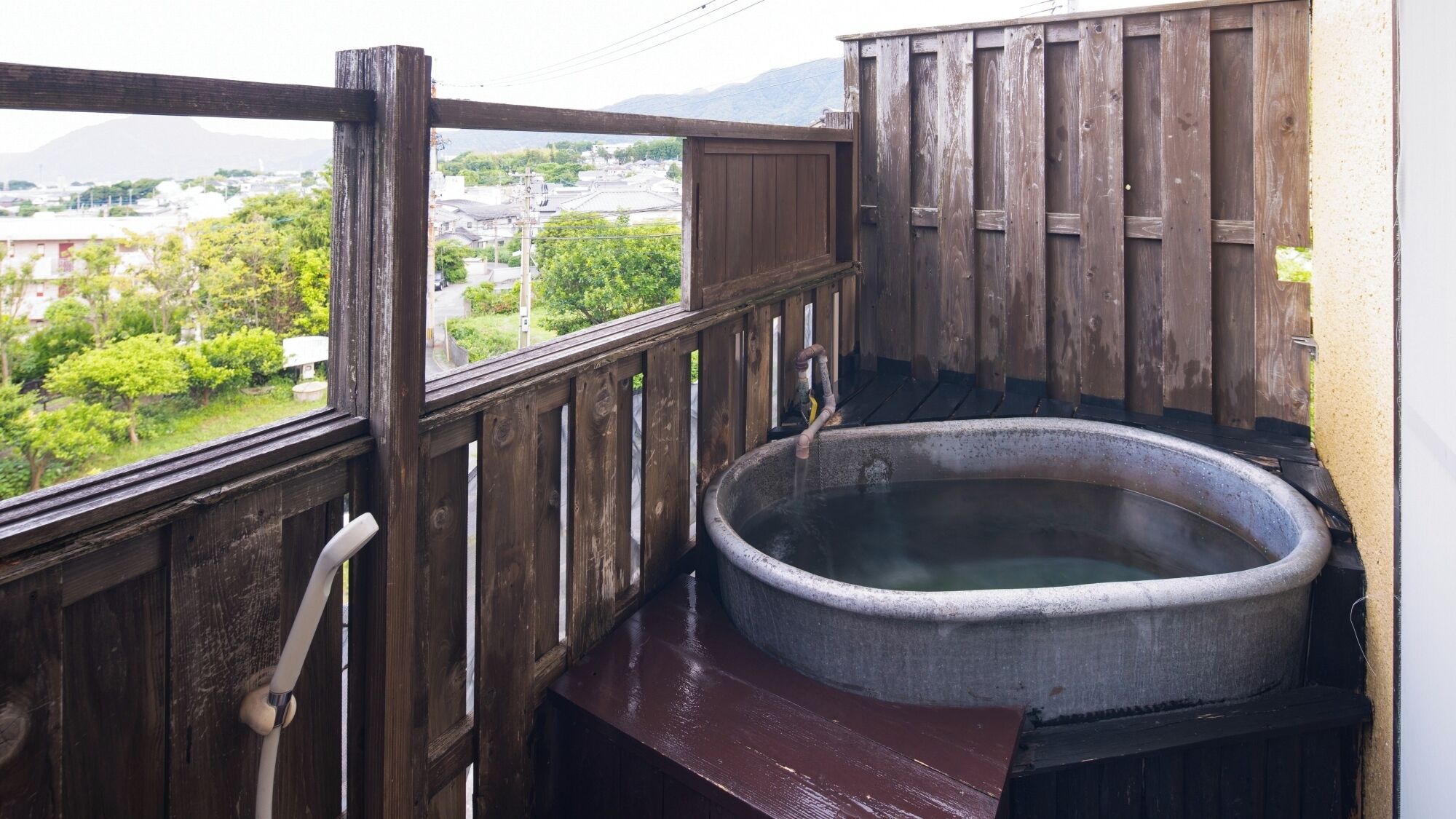 Ein Holzbalkon mit Whirlpool, Blick auf eine Stadt und ein Berg im Hintergrund.