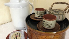 Ein Teeservice mit einer weißen Teekanne, zwei Tassen mit floralen Motiven und einem passenden Zuckerbehälter.