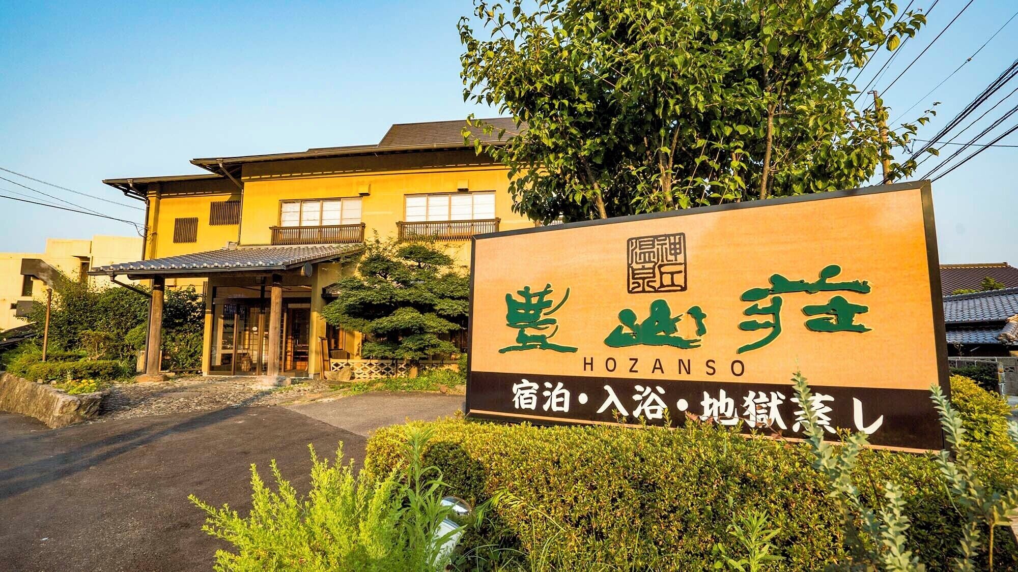 Un edificio japonés tradicional con un letrero que dice 'HOZANSO' y menciona 'aguas termales, onsen, baños'.