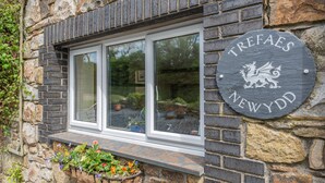 Un bâtiment en pierre avec une fenêtre et une enseigne sur laquelle on peut lire « Trefaes Newydd ».