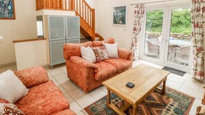 Un salon comprenant un canapé, une table basse, un escalier et une vue sur l’extérieur.