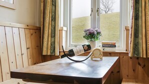 A wooden room with a window, a bottle of wine, and a small table. - The Smithy (Richmond)
