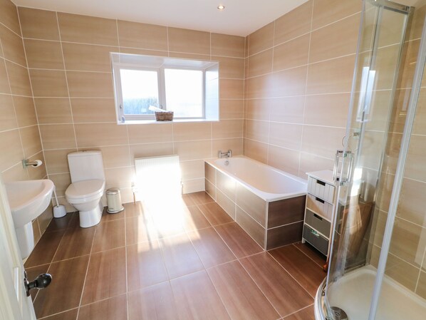 A modern bathroom with a toilet, bidet, bathtub, and shower.