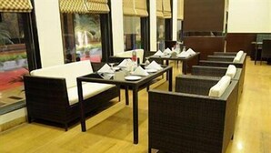 A hotel lobby with wicker furniture, a sofa, and a table with napkins and a bottle. - Pallavi Ávida (Panvel)