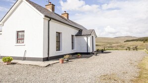 Una casa blanca con camino de grava, una chimenea y una antena parabólica.