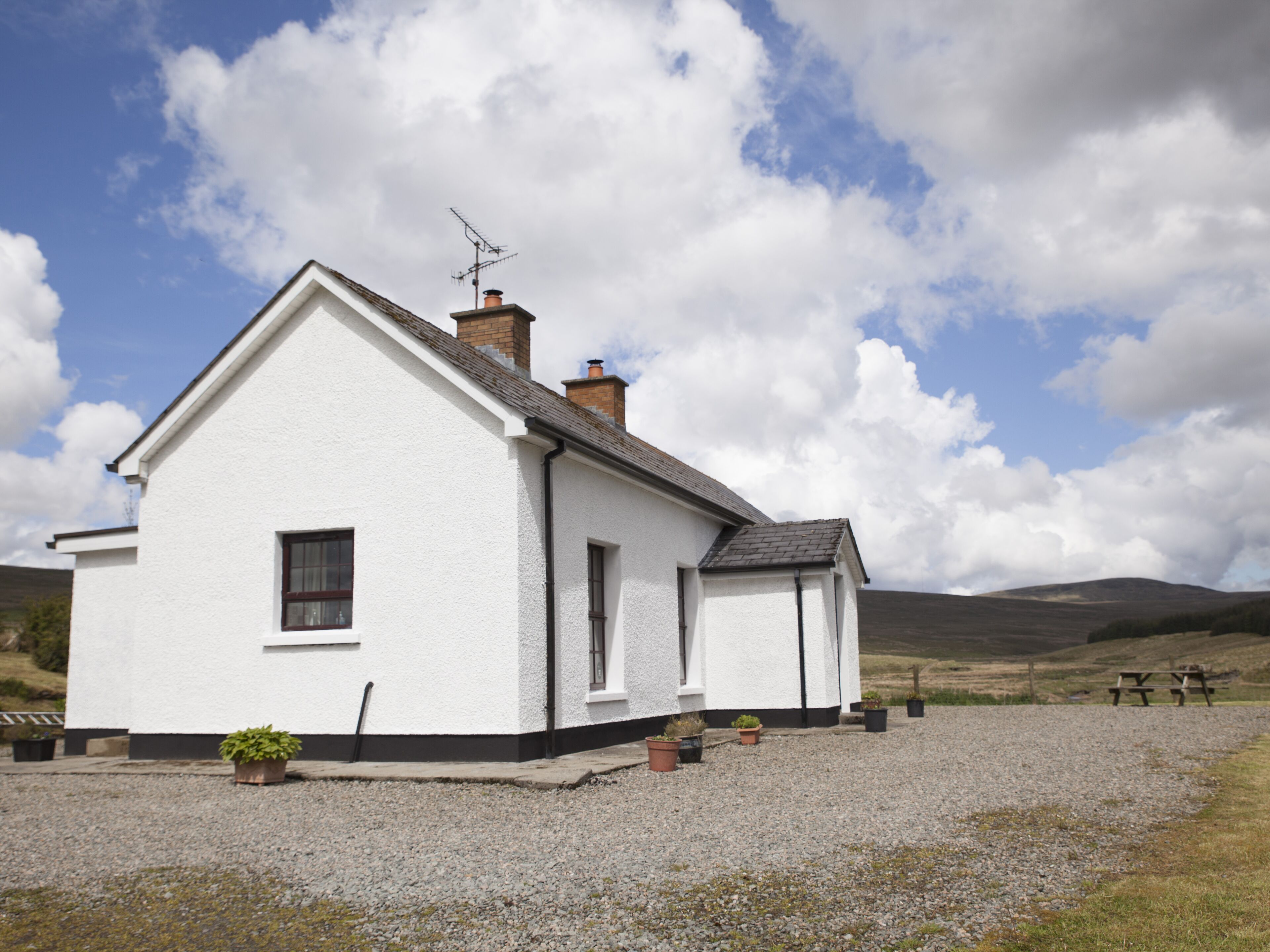 A white building with a black roof, a chimney, and a small window.