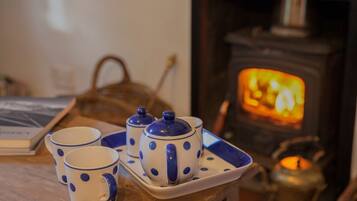 A cozy room with a fireplace, a tray with teacups and a teapot, and a candle on a table.