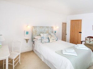 A neatly arranged bedroom with a bed, bedside table, chair, and a door. - Big House (Talsarnau)