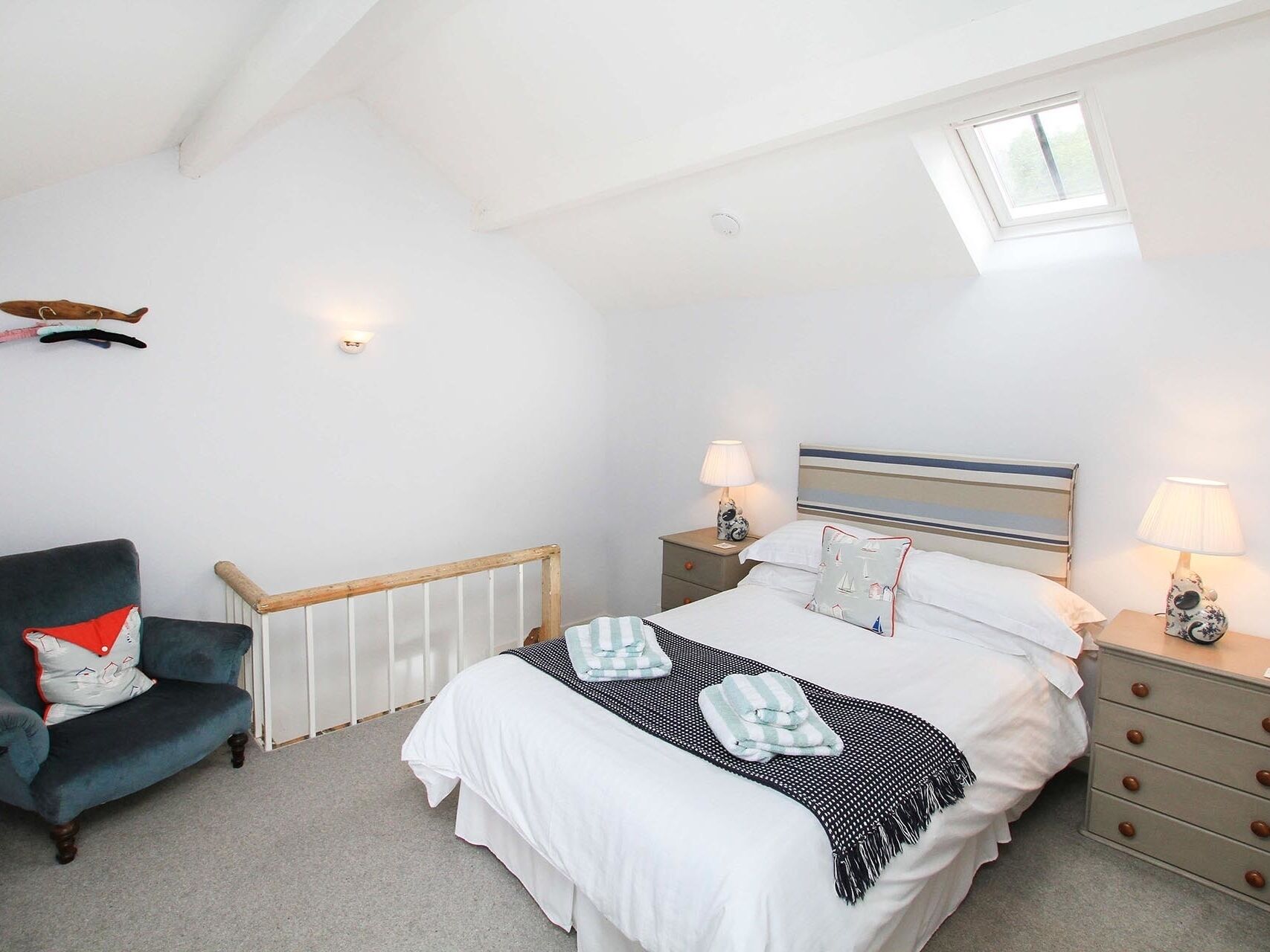 Een slaapkamer met een bed, een stoel, een nachtkastje, een lamp en een raam.