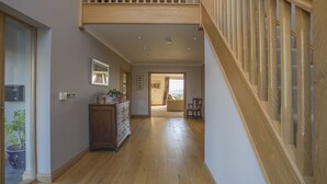 Un hall d’entrée spacieux, doté d’un plancher en bois, d’un escalier en bois et offrant une vue sur l’espace de vie.