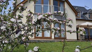 Une maison dotée d’une grande baie vitrée, d’un balcon et d’une pelouse bien entretenue.