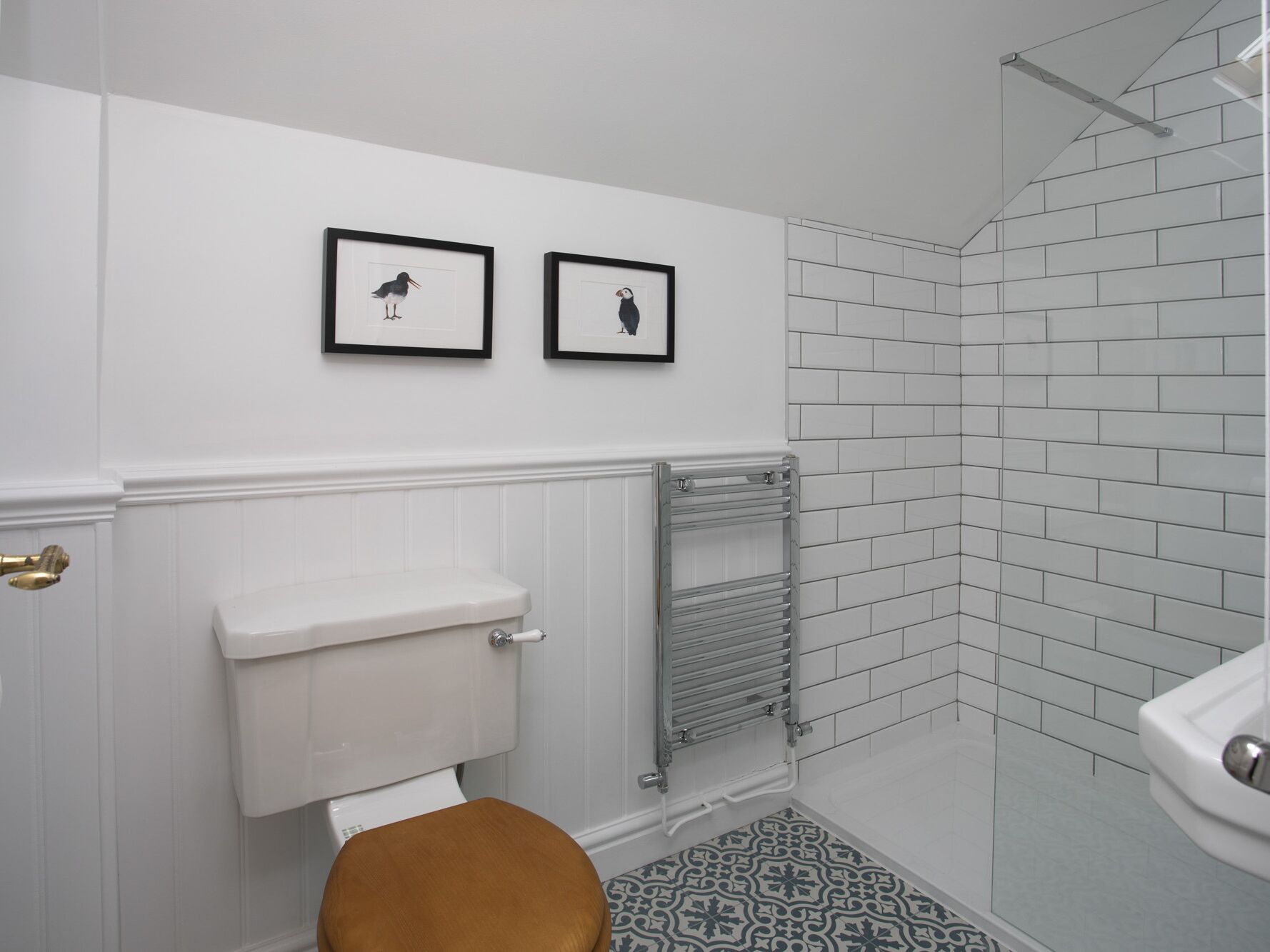 Ein Badezimmer mit Toilette, Handtuchhalter und Duschbereich mit weißen Fliesen.
