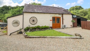 A small, single-story building with a wooden door and a wheel-like feature on the wall. - The Mill (Llandysul)