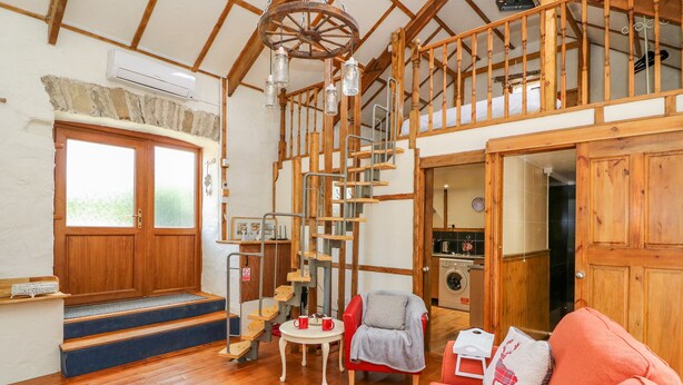 A cozy interior with a wooden staircase, a red rug, and a sofa. - The Mill (Llandysul)
