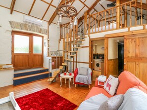 A cozy interior with a wooden staircase, a red rug, and a sofa. - The Mill (Llandysul)