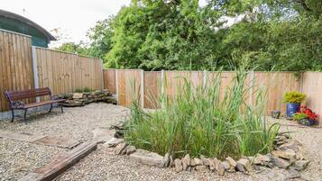 A garden area with a wooden bench, a gravel path, and a wooden fence.