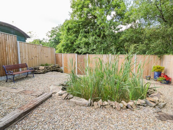 A garden area with a wooden bench, a gravel path, and a wooden fence. - The Mill (Llandysul)