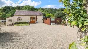 A building with a gravel driveway, a wooden door, and a small garden area. - The Mill (Llandysul)