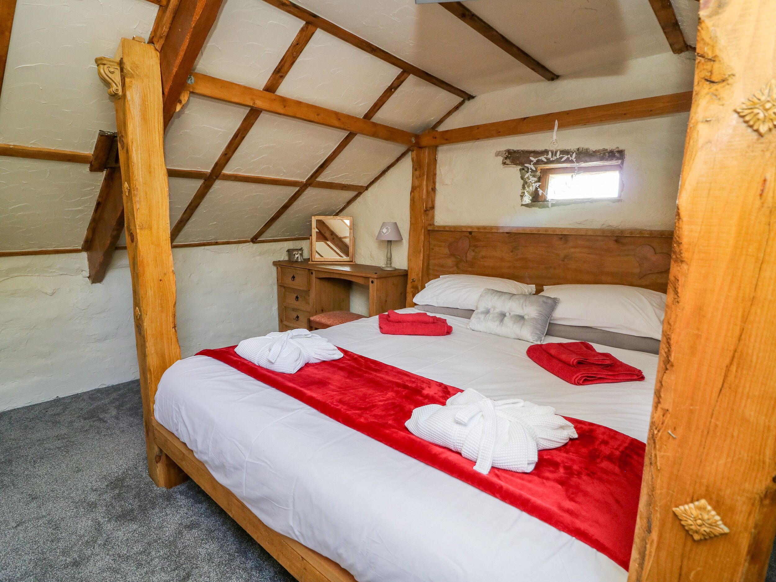 Een gezellige slaapkamer met een houten bed, nachtkastje en spiegel.