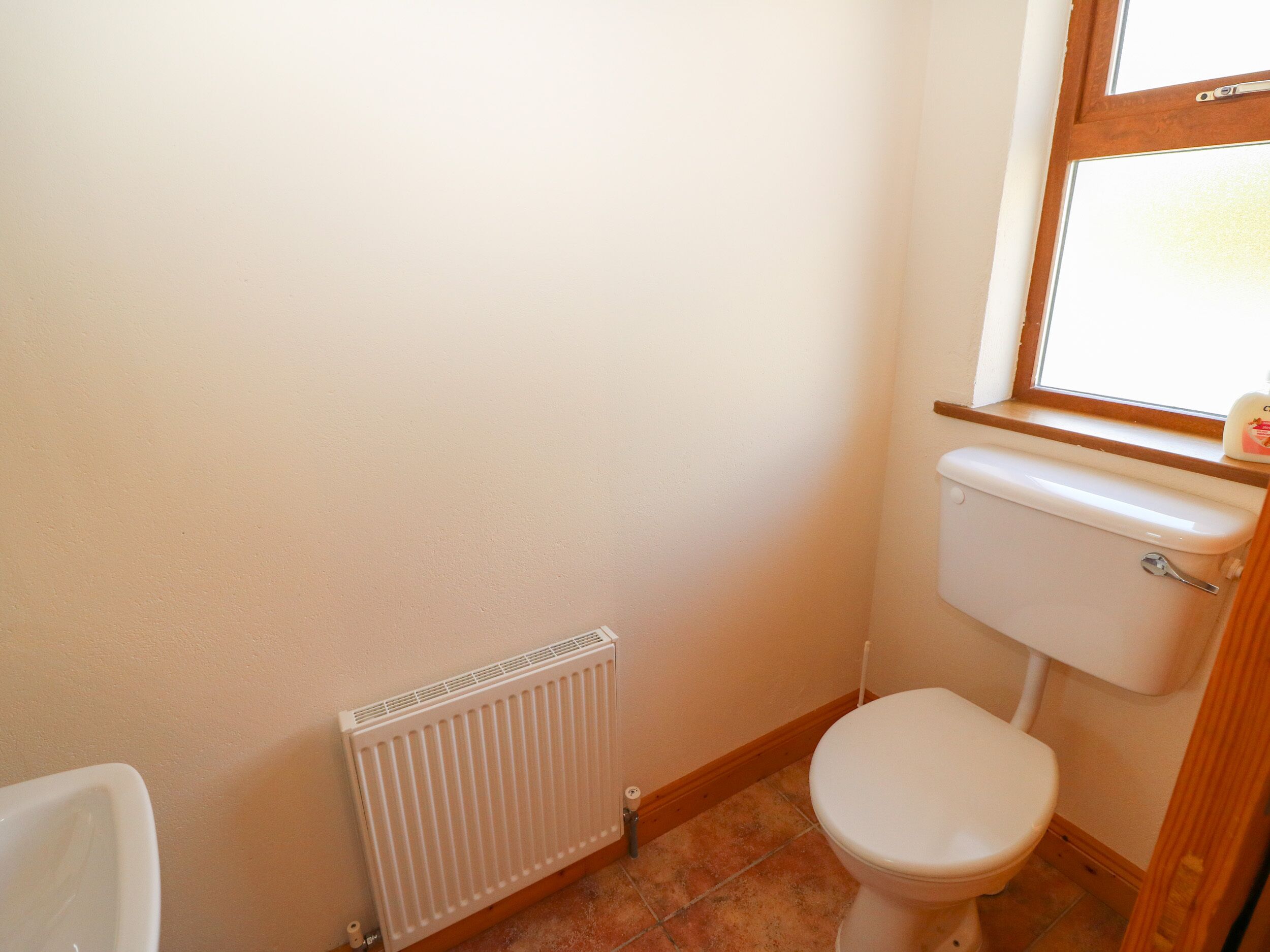 A small, clean bathroom with a white toilet, a radiator, and a window.