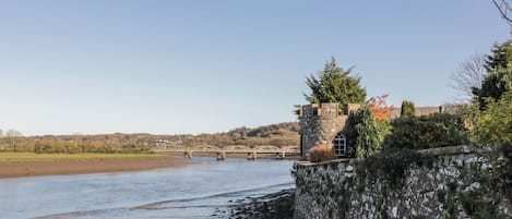 A stone wall with a castle-like structure, a river, and a bridge in the background.