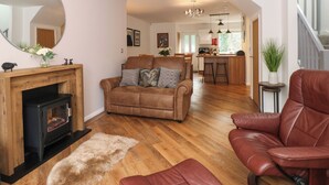 A spacious living room with a fireplace, leather sofas, and a wooden floor. - The Sanctuary (Windermere)