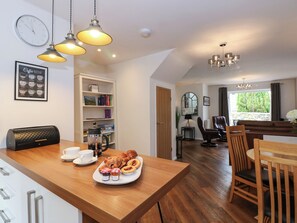 Una cocina moderna con una mesa de madera dispuesta para el desayuno, incluyendo cruasanes, mermelada y una cafetera.