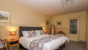 A neatly arranged bedroom with a large bed, bedside lamps, a wooden nightstand, and a chair. - 3 Springhaven (Godalming)