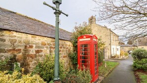 A traditional stone building with a red telephone booth and a green street lamp. - 3 Springhaven (Godalming)