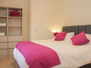 A neatly made bed with white and pink bedding, a grey headboard, and a bedside lamp. - Black Lion Barn Retreat (Shrewsbury)