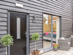 A dark wooden door with a small window, a sliding glass door, and two potted plants.