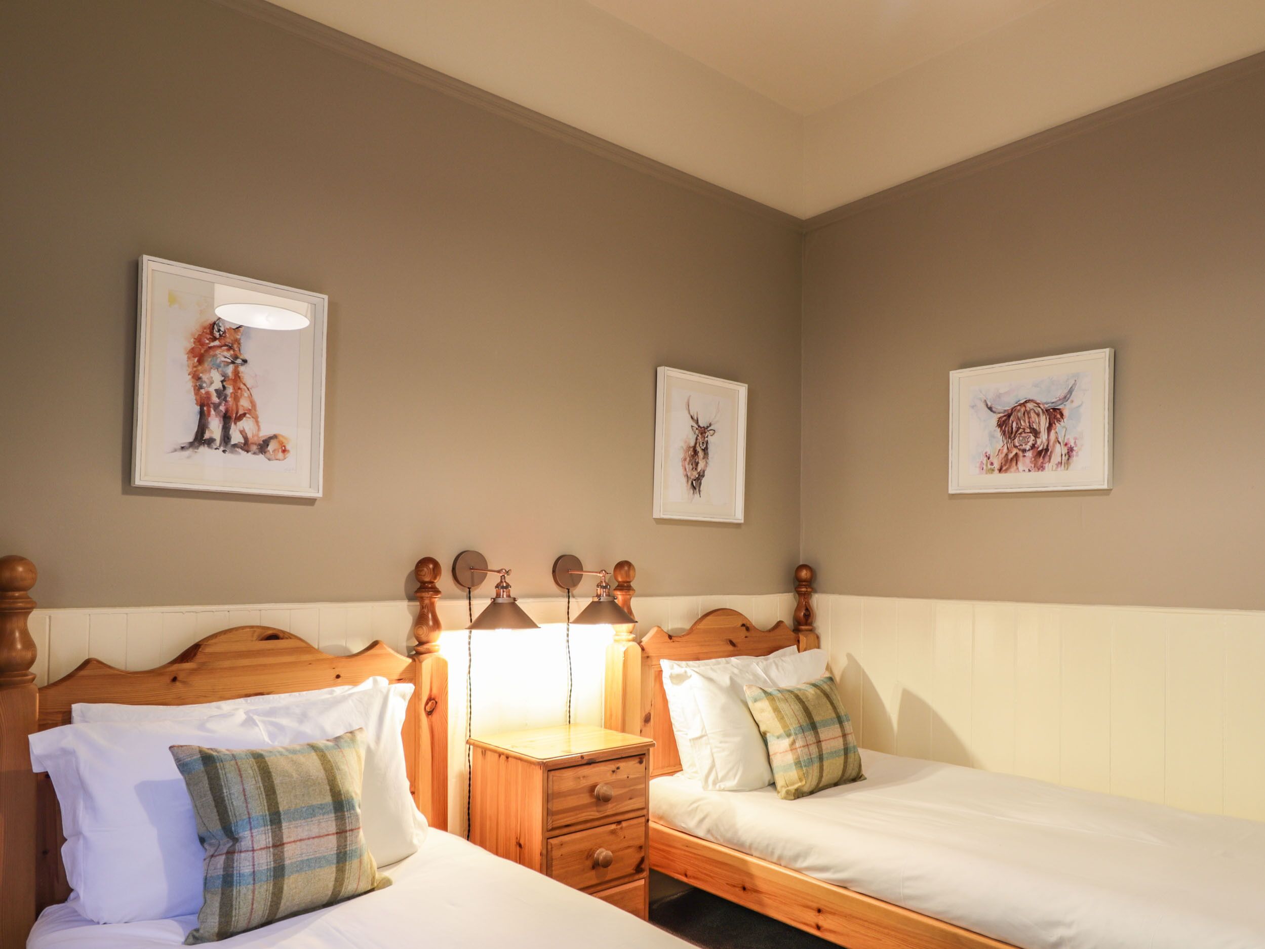 Une chambre à coucher avec deux lits en bois, une table de chevet et des lampes fixées au mur.