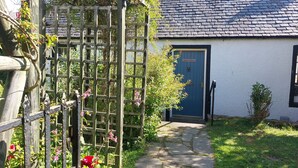 Un cottage con un vialetto in pietra che conduce a una porta blu con su scritto "Lydia Cottage".