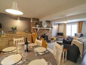 A dining area with a table set for four, a fireplace, a TV, and a sofa in a living room. - Harbour Reach (Weymouth)