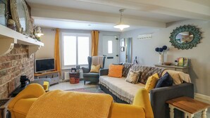 A living room with a fireplace, a sofa, a chair, and a television. - Harbour Reach (Weymouth)