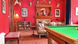 A room with a pool table, a fireplace, bookshelves, and antler decorations on the wall. - Paye House - Cromarty (Cromarty)