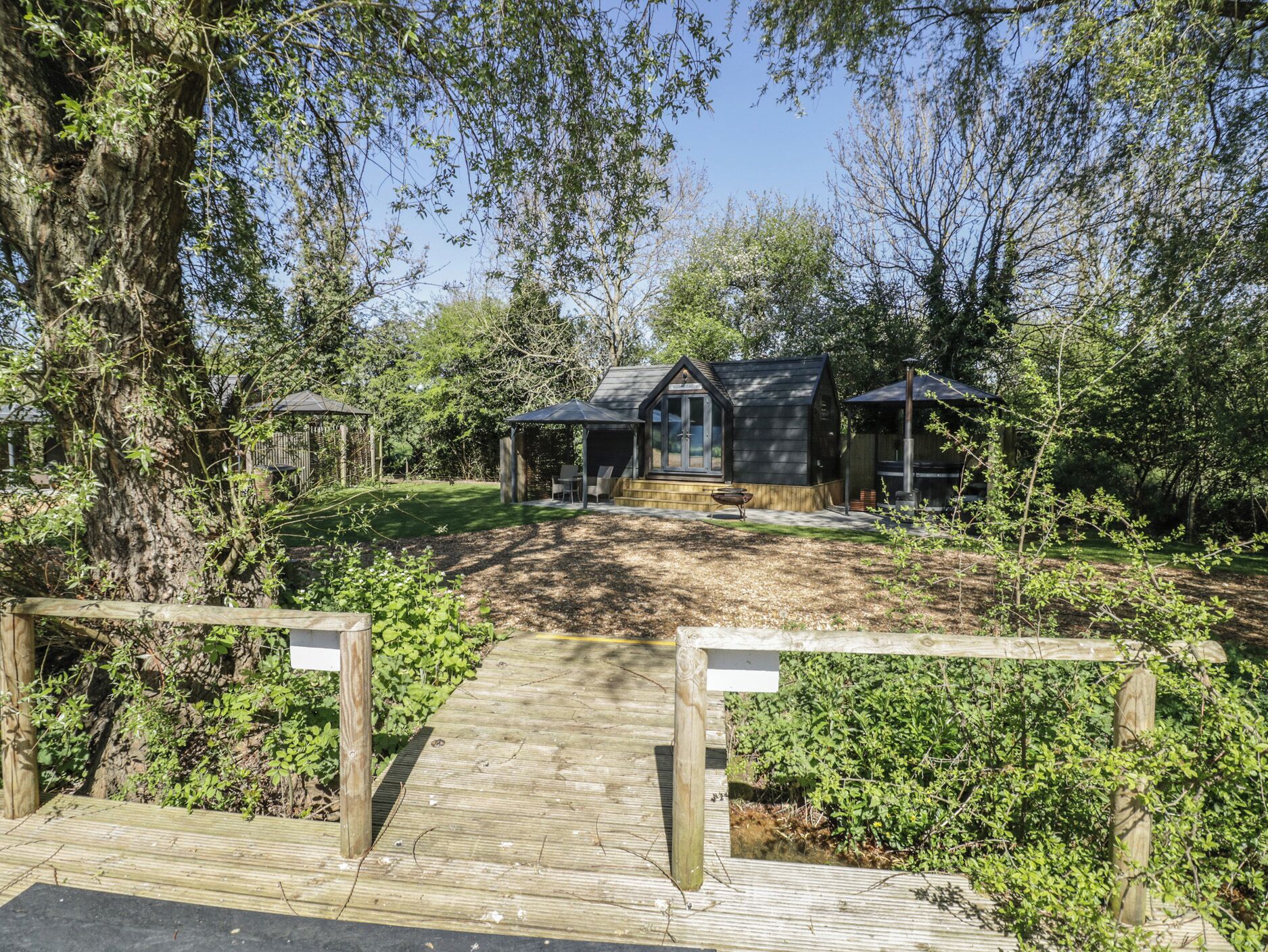 A wooden deck leading to a lodge with a covered patio and a small outdoor kitchen area.
