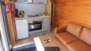 Een kleine keuken met een koelkast, oven en magnetron, een klein aanrecht en een houten plafond.